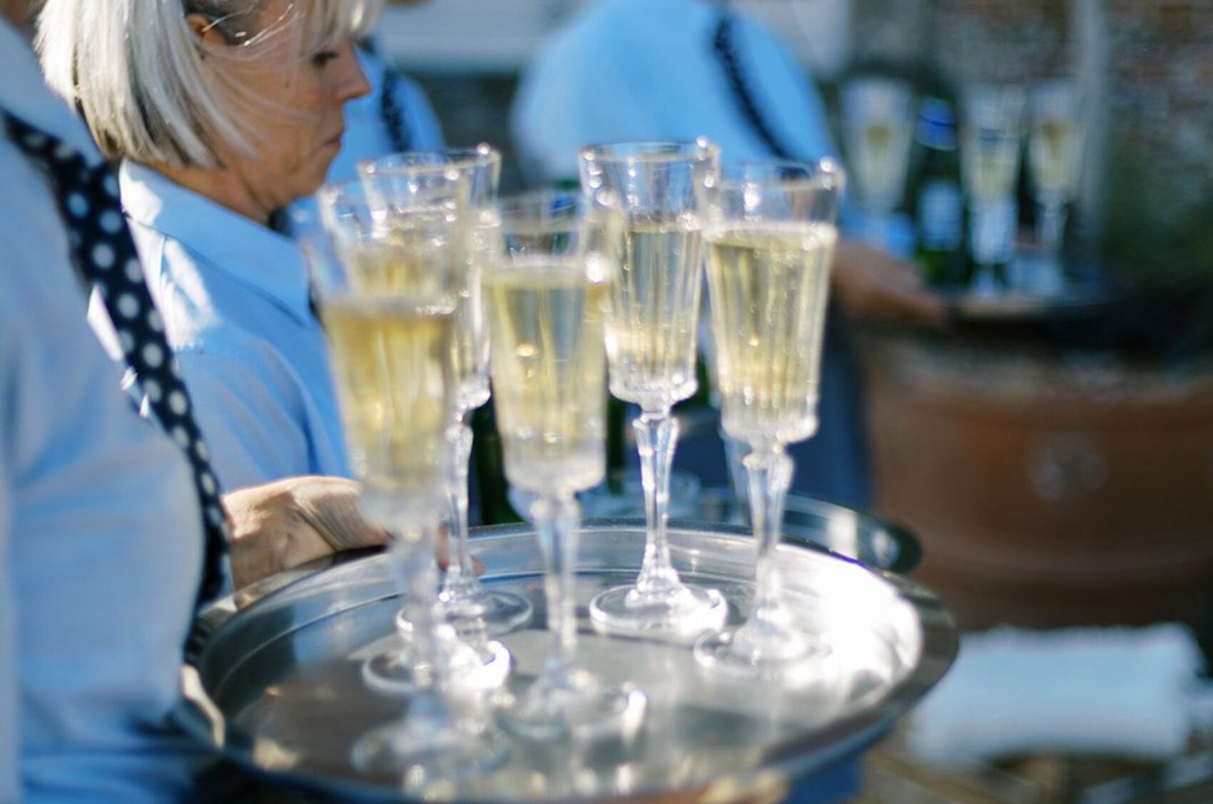 Waiting staff holding trays of champagne in blue uniform