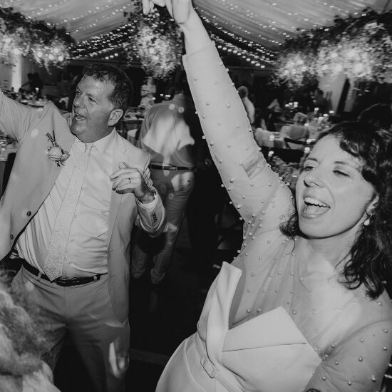Wedding guests dancing together on a busy dance floor during the evening reception.